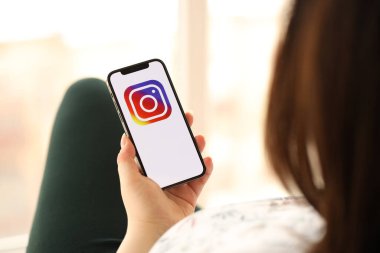 KYIV, UKRAINE - Nisan 1, 2024 Instagram simgesi akıllı telefon ekranında kapalı alanda genç kadınların elinde. iPhone uygulaması kullanan kadın