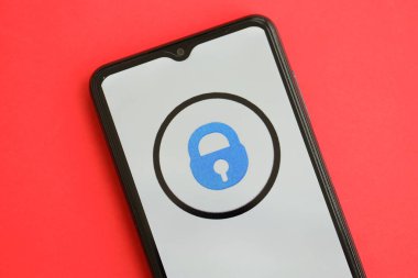 KYIV, UKRAINE - 1 Nisan 2024 OnlyFans simgesi kırmızı masadaki akıllı telefon ekranında. Parlak kırmızı arkaplanda uygulama logosuna sahip iPhone görüntüsü