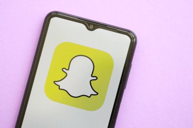 KYIV, UKRAINE - 1 Nisan 2024 Snapchat simgesi mor masadaki akıllı telefon ekranında. Leylak arka planında uygulama logosu olan iPhone görüntüsü