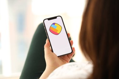 KYIV, UKRAINE - Nisan 1, 2024 Sharechat simgesi akıllı telefon ekranında kapalı alanda genç kadınların elinde. iPhone uygulaması kullanan kadın