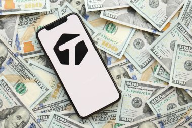 KYIV, UKRAINE - Nisan 1, 2024 Akıllı telefon ekranında etiketlenmiş simge ve birçok kullanım dışı para. Uygulama logolu iPhone görüntüsü ve bir sürü yüz dolarlık banknotlar