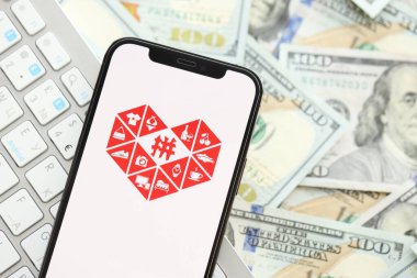 KYIV, UKRAINE - Nisan 1, 2024 Pinduoduo simgesi birçok kullanım dışı para banknotlarında akıllı telefon ekranında. Uygulama logosuna sahip iPhone görüntüsü ve beyaz klavyeli dolar banknotları