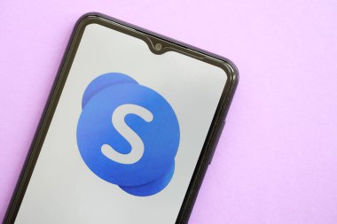 KYIV, UKRAINE - 1 Nisan 2024 Skype simgesi mor masadaki akıllı telefon ekranında. Leylak arka planında uygulama logosu olan iPhone görüntüsü