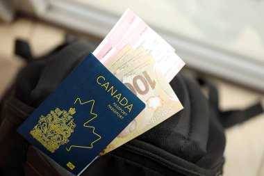Kanada pasaportu ve uçak biletlerinin olduğu para faturaları yakın plan.