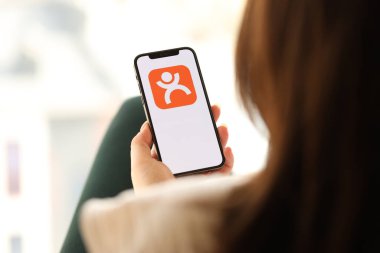 KYIV, UKRAINE - Nisan 1, 2024 Dianping platform simgesi kapalı alandaki genç kadınların elinde akıllı telefon ekranında. iPhone uygulaması kullanan kadın