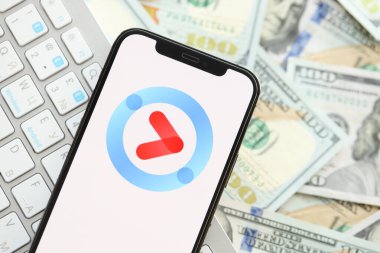 KYIV, UKRAINE - 1 Nisan 2024 Youku simgesi birçok kullanışlı para banknotlarında akıllı telefon ekranında. Uygulama logosuna sahip iPhone görüntüsü ve beyaz klavyeli dolar banknotları