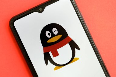 KYIV, UKRAINE - 1 Nisan 2024 Tencent QQ simgesi kırmızı masadaki akıllı telefon ekranında. Parlak kırmızı arkaplanda uygulama logosuna sahip iPhone görüntüsü