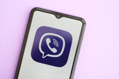 KYIV, UKRAINE - 1 Nisan 2024 Viber kurye simgesi mor masadaki akıllı telefon ekranında. Leylak arka planında uygulama logosu olan iPhone görüntüsü