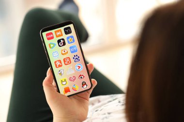 KYIV, UKRAINE - Nisan 1, 2024 Asya uygulamaları simgesi akıllı telefon ekranında kapalı alanda genç kadınların elinde. iPhone uygulaması kullanan kadın