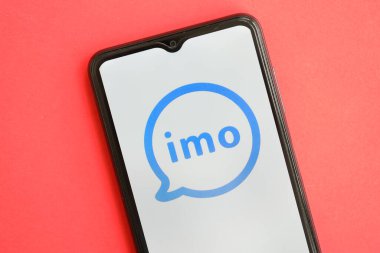 KYIV, UKRAINE - 1 Nisan 2024 İmo kurye simgesi kırmızı masadaki akıllı telefon ekranında. Parlak kırmızı arkaplanda uygulama logosuna sahip iPhone görüntüsü