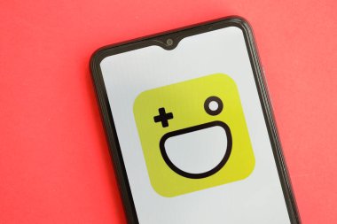 KYIV, UKRAINE - 1 Nisan 2024 Hago simgesi kırmızı masadaki akıllı telefon ekranında. Parlak kırmızı arkaplanda uygulama logosuna sahip iPhone görüntüsü