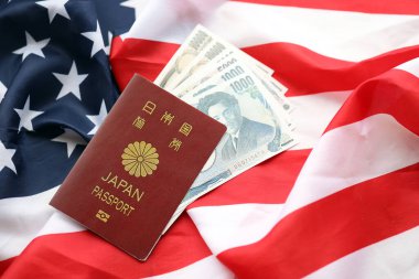 Japan passport with japanese yen money bills on United States flag close up clipart