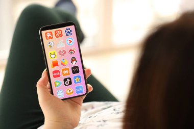 KYIV, UKRAINE - Nisan 1, 2024 Asya uygulamaları simgesi akıllı telefon ekranında kapalı alanda genç kadınların elinde. iPhone uygulaması kullanan kadın