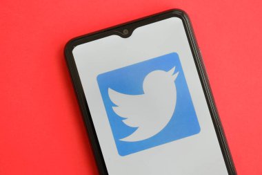 KYIV, UKRAINE - 1 Nisan 2024 Twitter simgesi kırmızı masadaki akıllı telefon ekranında. Parlak kırmızı arkaplanda uygulama logosuna sahip iPhone görüntüsü