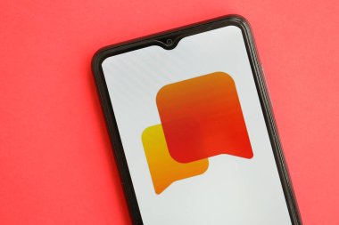 KYIV, UKRAINE - 1 Nisan 2024 Helo simgesi kırmızı masadaki akıllı telefon ekranında. Parlak kırmızı arkaplanda uygulama logosuna sahip iPhone görüntüsü