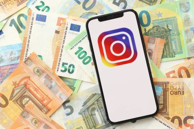 KYIV, UKRAINE - Nisan 1, 2024 Instagram simgesi birçok avro para bankasında akıllı telefon ekranında. Avrupa para birimi euro banknotlu uygulama logosuyla iPhone görüntüsü