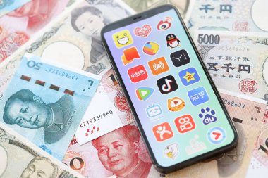 KYIV, UKRAINE - 1 Nisan 2024 Asya uygulamaları simgesi birçok Asya para bankasında akıllı telefon ekranında. Japon yen ve Çin Yuan banknotları içeren uygulamalı iPhone ekranı