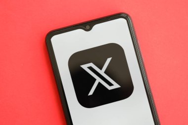KYIV, UKRAINE - 1 Nisan 2024 Twitter X simgesi kırmızı masadaki akıllı telefon ekranında. Parlak kırmızı arkaplanda uygulama logosuna sahip iPhone görüntüsü