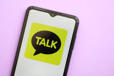 KYIV, UKRAINE - 1 Nisan 2024 KakaoTalk kurye simgesi mor masadaki akıllı telefon ekranında. Leylak arka planında uygulama logosu olan iPhone görüntüsü