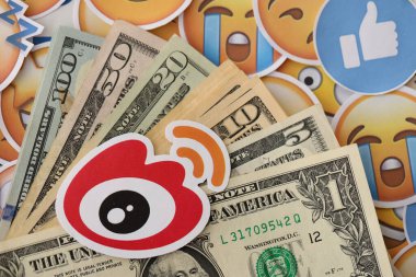 KYIV, UKRAINE - 20 Nisan, 2024 Weibo logosu ve birçok kullanım parası. Birçok emoji reaksiyonuna ilişkin ünlü sosyal ağ platformu ve dolar banknotlarının sembolü