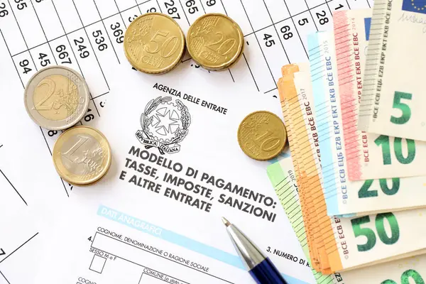 stock image KYIV, UKRAINE - APRIL 20, 2024 Agenzia Delle Entrate logo from blank tax form and many euro banknotes on office table and pen