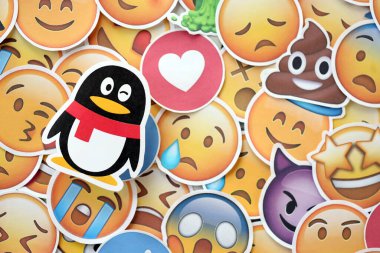 KYIV, UKRAINE - 20 Nisan 2024 Tencent QQ logosu ve Emoji sarı yüzlü büyük çıkartmalar. Emoji, elektronik mesajlarda ve web sayfalarında kullanılan ve metne gömülü bir resim veya gülen yüzdür.