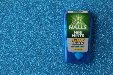 KYIV, UKRAINE - 20 Nisan 2024 Halls Mini nane şekeri bükülmüş enerji vitamini b6 küçük mavi kutu içinde sert nane şekerleri mavi arka planda yakın plan