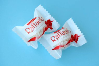 KYIV, UKRAINE - 20 Nisan 2024 Ferrero Raffaello premium tatlılar İtalyan çikolatacı Ferrero SpA tarafından mavi arka planda üretildi. Raffaello şekerlemeleri küresel bir hindistan cevizi badem şekerlemesidir.