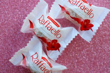 KYIV, UKRAINE - 20 Nisan 2024 Ferrero Raffaello premium tatlılar İtalyan çikolatacı Ferrero SpA tarafından pembe arka planda üretildi. Raffaello şekerlemeleri küresel bir hindistan cevizi badem şekerlemesidir.