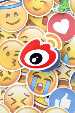 KYIV, UKRAINE - 20 Nisan 2024 Weibo logosu ve Emoji sarı yüzlü büyük çıkartmalar. Emoji, elektronik mesajlarda ve web sayfalarında kullanılan ve metne gömülü bir resim veya gülen yüzdür.