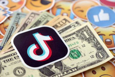 KYIV, UKRAINE - 20 Nisan, 2024 TikTok logosu ve birçok kullanım parası. Birçok emoji reaksiyonuna ilişkin ünlü sosyal ağ platformu ve dolar banknotlarının sembolü