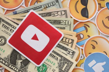 KYIV, UKRAINE - 20 Nisan 2024 YouTube logosu ve birçok kullanım dışı para. Birçok emoji reaksiyonuna ilişkin ünlü sosyal ağ platformu ve dolar banknotlarının sembolü