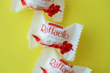 KYIV, UKRAINE - 20 Nisan 2024 Ferrero Raffaello premium tatlılar İtalyan çikolatacı Ferrero SpA tarafından sarı arka planda üretildi. Raffaello şekerlemeleri küresel bir hindistan cevizi badem şekerlemesidir.
