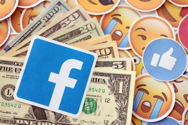 KYIV, UKRAINE - 20 Nisan, 2024 Facebook logosu ve birçok kullanım dışı para. Birçok emoji reaksiyonuna ilişkin ünlü sosyal ağ platformu ve dolar banknotlarının sembolü