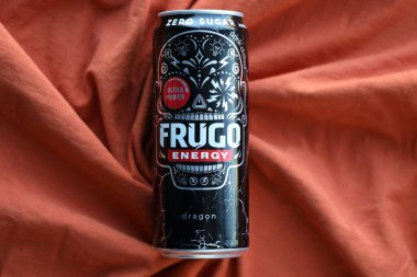 KYIV, UKRAINE - 20 Nisan 2024 Frugo enerji içeceği turuncu kumaş üzerinde siyah teneke kutuda. Frugo artık Gıda Bakımı Polonya 'ya ait.