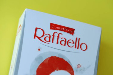 KYIV, UKRAINE - 20 Nisan 2024 Ferrero Raffaello premium tatlılar İtalyan çikolatacı Ferrero SpA tarafından sarı arka planda üretildi. Raffaello şekerlemeleri küresel bir hindistan cevizi badem şekerlemesidir.