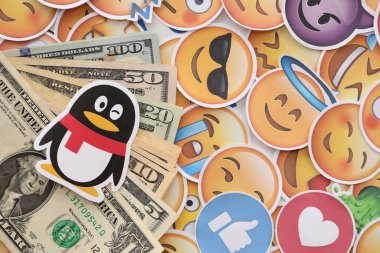 KYIV, UKRAINE - 20 Nisan 2024 Tencent QQ logosu ve pek çok kullanıcı para faturası. Birçok emoji reaksiyonuna ilişkin ünlü sosyal ağ platformu ve dolar banknotlarının sembolü