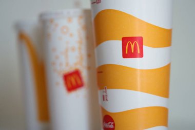 KYIV, UKRAINE - 20 Nisan 2024 Cold McDonalds Gri Masa üzerinde şirket logosu olan içecekler. Red McDonalds tek kullanımlık kağıt bardakların üzerine logosu
