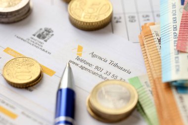 KYIV, UKRAINE - 20 Nisan 2024 Agencia Tributaria logosu boş vergi formundan ve ofis masası ve kaleminde birçok euro banknotları