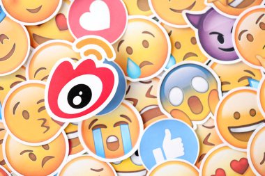 KYIV, UKRAINE - 20 Nisan 2024 Weibo logosu ve Emoji sarı yüzlü büyük çıkartmalar. Emoji, elektronik mesajlarda ve web sayfalarında kullanılan ve metne gömülü bir resim veya gülen yüzdür.
