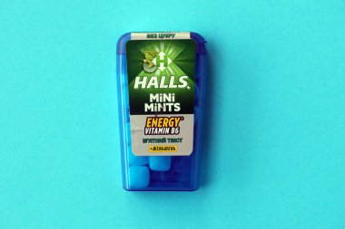 KYIV, UKRAINE - 20 Nisan 2024 Halls Mini nane şekeri bükülmüş enerji vitamini b6 küçük mavi kutu içinde sert nane şekerleri mavi arka planda yakın plan