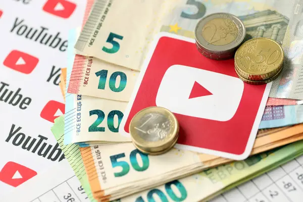 stock image KYIV, UKRAINE - APRIL 20, 2024 YouTube logo and many euro money bills. Symbol of famous social network platform and european currency banknotes close up