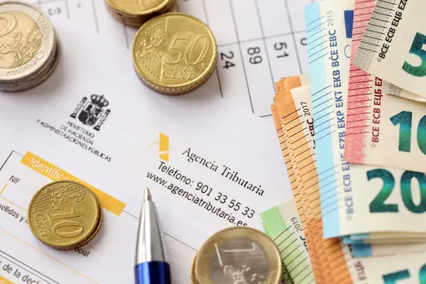 KYIV, UKRAINE - 20 Nisan 2024 Agencia Tributaria logosu boş vergi formundan ve ofis masası ve kaleminde birçok euro banknotları