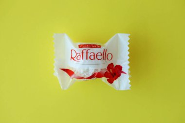 KYIV, UKRAINE - 20 Nisan 2024 Ferrero Raffaello premium tatlılar İtalyan çikolatacı Ferrero SpA tarafından sarı arka planda üretildi. Raffaello şekerlemeleri küresel bir hindistan cevizi badem şekerlemesidir.