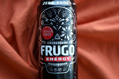 KYIV, UKRAINE - 20 Nisan 2024 Frugo enerji içeceği turuncu kumaş üzerinde siyah teneke kutuda. Frugo artık Gıda Bakımı Polonya 'ya ait.