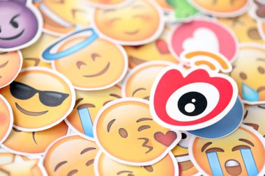 KYIV, UKRAINE - 20 Nisan 2024 Weibo logosu ve Emoji sarı yüzlü büyük çıkartmalar. Emoji, elektronik mesajlarda ve web sayfalarında kullanılan ve metne gömülü bir resim veya gülen yüzdür.