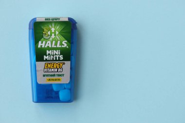 KYIV, UKRAINE - 20 Nisan 2024 Halls Mini nane şekeri bükülmüş enerji vitamini b6 küçük mavi kutu içinde sert nane şekerleri mavi arka planda yakın plan