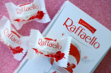 KYIV, UKRAINE - 20 Nisan 2024 Ferrero Raffaello premium tatlılar İtalyan çikolatacı Ferrero SpA tarafından pembe arka planda üretildi. Raffaello şekerlemeleri küresel bir hindistan cevizi badem şekerlemesidir.