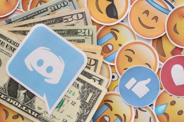 KYIV, UKRAINE - 20 Nisan 2024 Discord logosu ve birçok kullanım dışı para. Birçok emoji reaksiyonuna ilişkin ünlü sosyal ağ platformu ve dolar banknotlarının sembolü