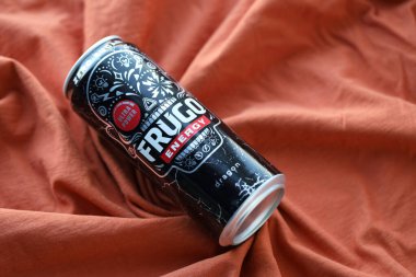 KYIV, UKRAINE - 20 Nisan 2024 Frugo enerji içeceği turuncu kumaş üzerinde siyah teneke kutuda. Frugo artık Gıda Bakımı Polonya 'ya ait.